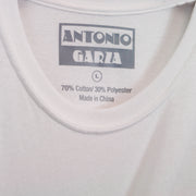 Close up of the inside neck print in gray text "Antonio Garza" "L""70% Cotton/30% Polyester""made in china" on a white tee.