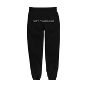 Photo of the black sweatpants lying flat.  "Not Thriving" text across the crotch area in silver rhinestones.