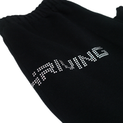 Close up of top of black sweatpants lying flat, text visible is "Hriving" in silver rhinestones.