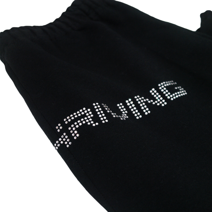 Close up of top of black sweatpants lying flat, text visible is "Hriving" in silver rhinestones.